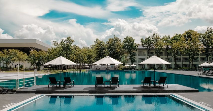 Resorts - Black Outdoor Lounge Chair in Between Blue Swimming Pool Under White Cloudy Blue Sky